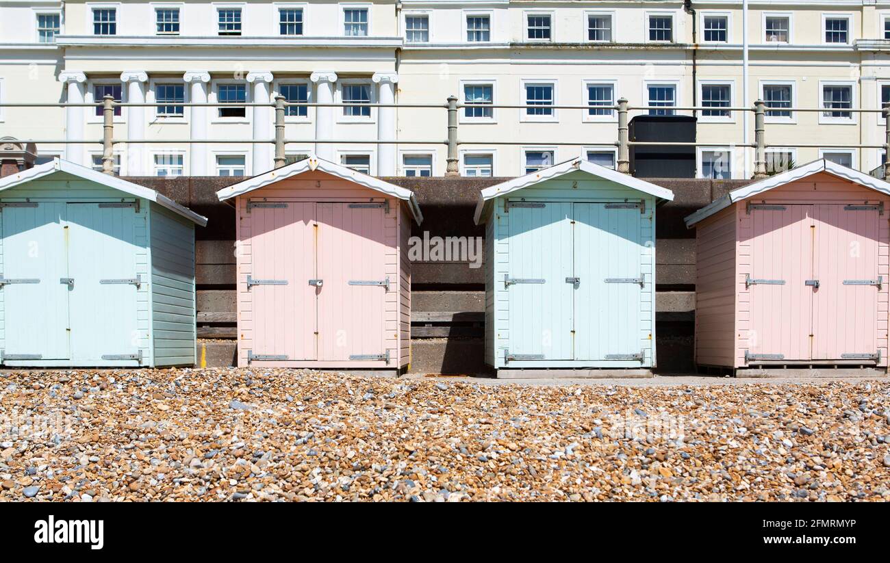 Strandhütten in Pastellfarben mit weißem Hotel in St. Leonards East Sussex Stockfoto