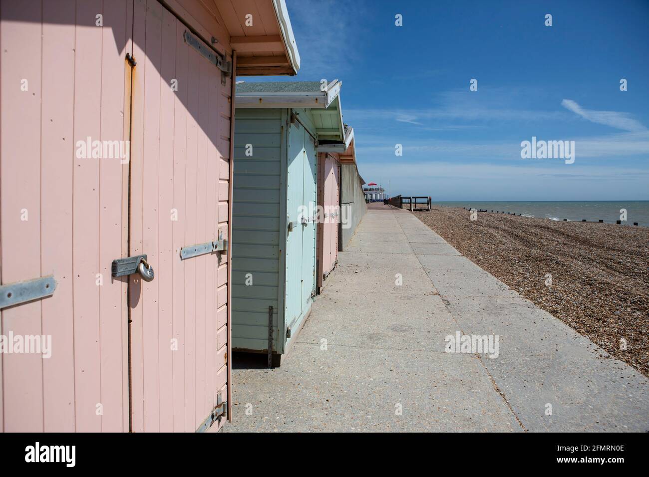 Strandhütten in Pastellfarben mit weißem Hotel in St. Leonards East Sussex Stockfoto