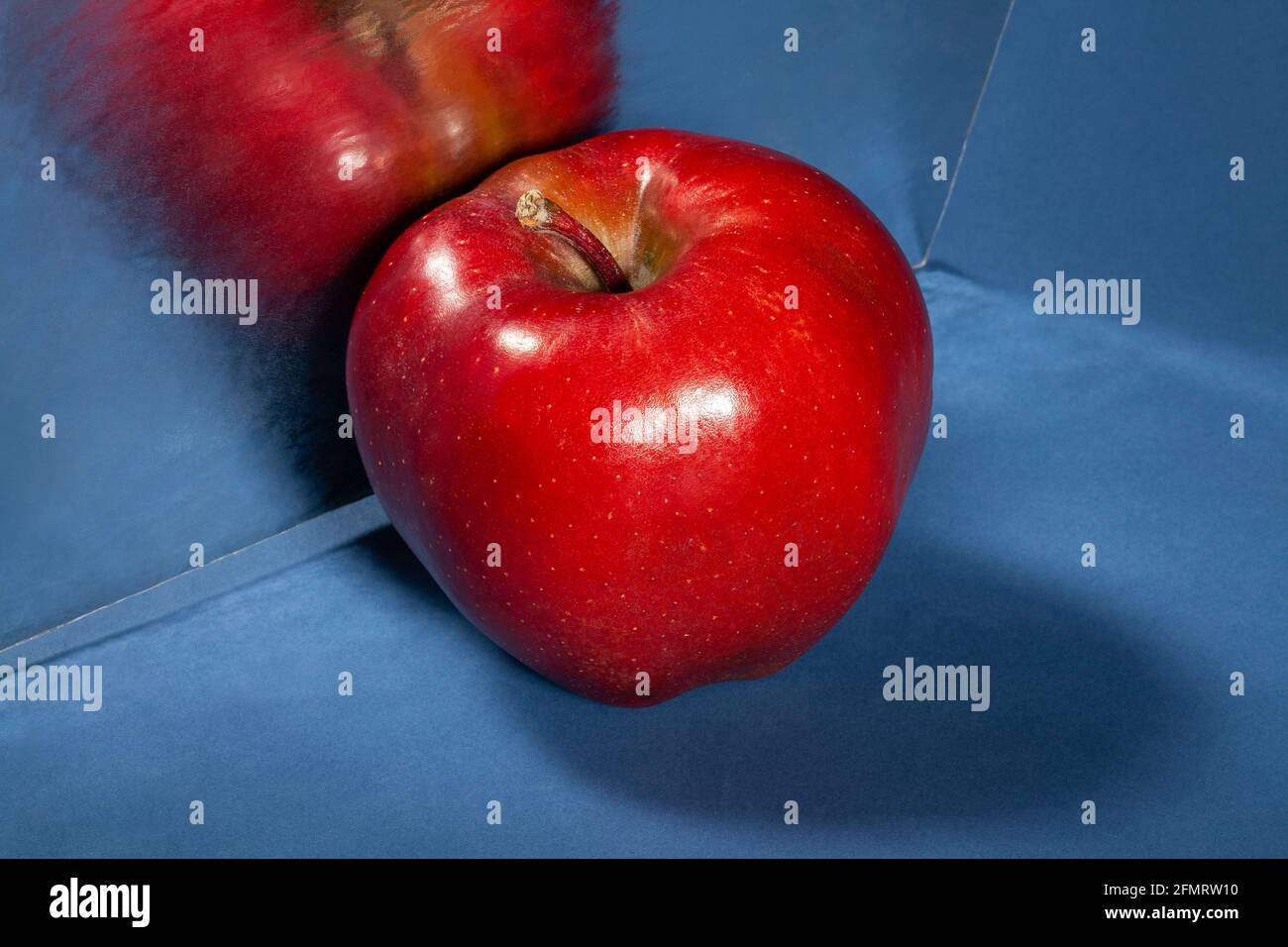 Verspiegelter roter köstlicher Apfel auf blauem Hintergrund Stockfoto