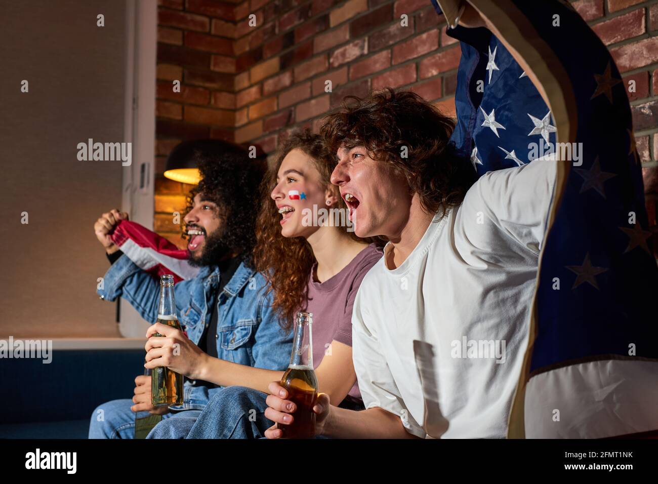 Diverse Sportfans feiern den Sieg zu Hause. Leidenschaftliche Unterstützer brüllen beim Fernsehen, jubeln zusammen, brüllen emotional Stockfoto