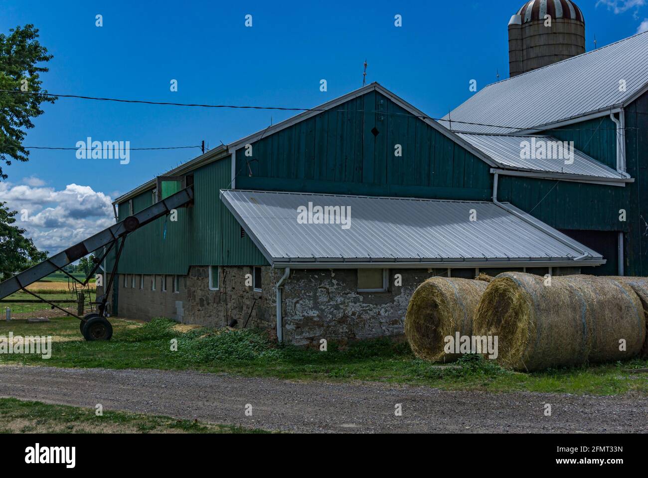 Hamilton, Ontario, Kanada, August 2016 - Scheune und Silo auf Ackerland mit davor gestapelten Heuballen Stockfoto