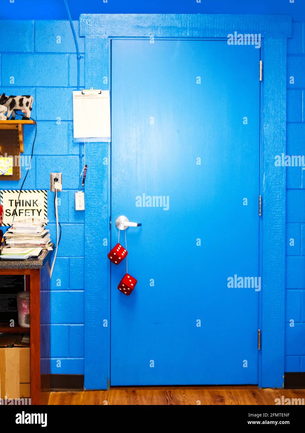 Hellblaue Tür im Computerraum mit Schild „Think Safety“ Und Stapel von Handbüchern - verschwommene Würfel hängen von der Tür Griff Stockfoto