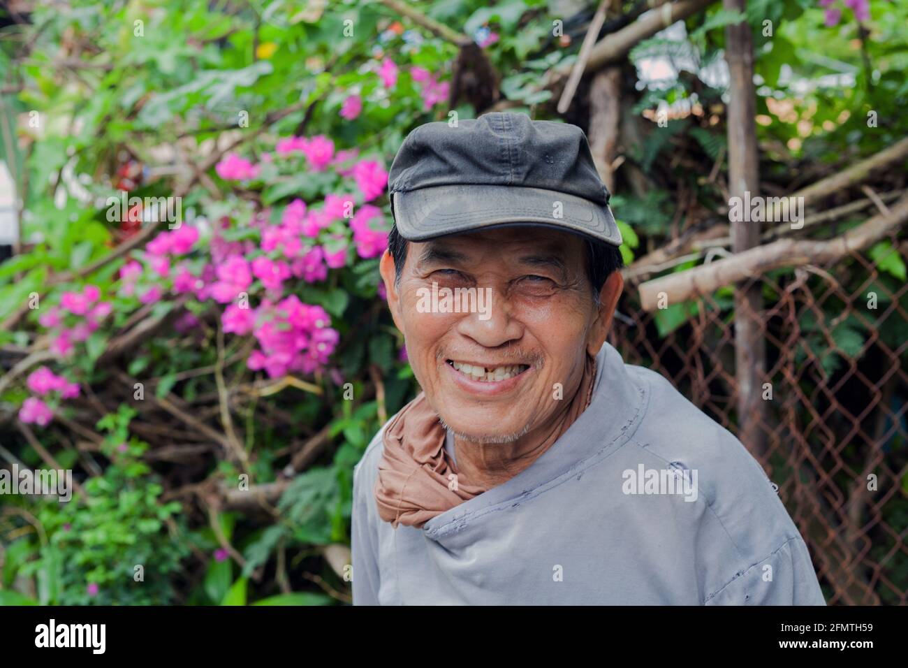 Älterer vietnamesischer Gärtner mit fehlenden Zähnen lächelt für Porträt, Hoi an, Vietnam Stockfoto