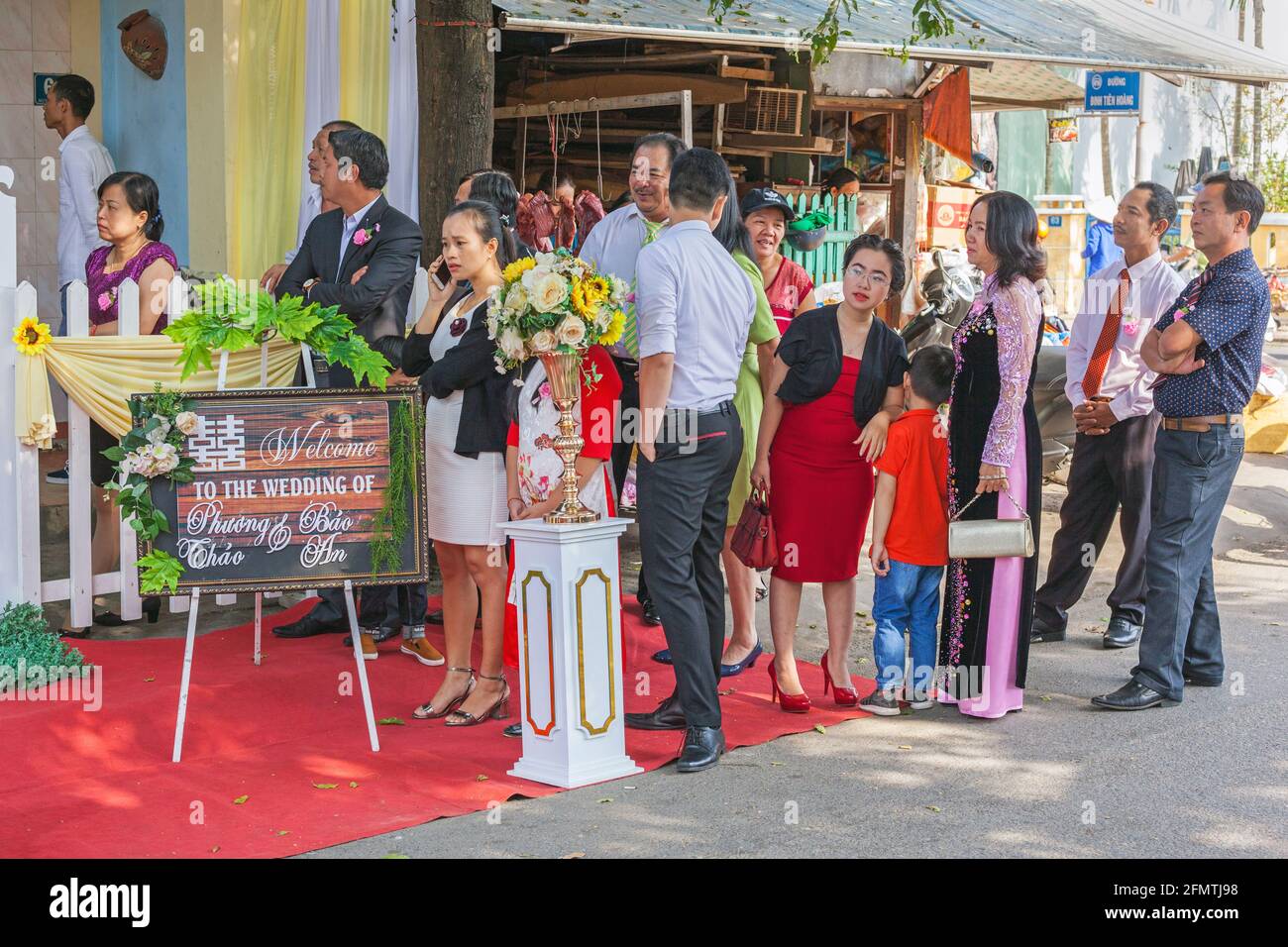 Vietnamesische Hochzeitsgäste, die Schlange stehen, um Zugang zu einem Hochzeitsempfang auf der Straße, Hoi an, Vietnam, zu erhalten Stockfoto