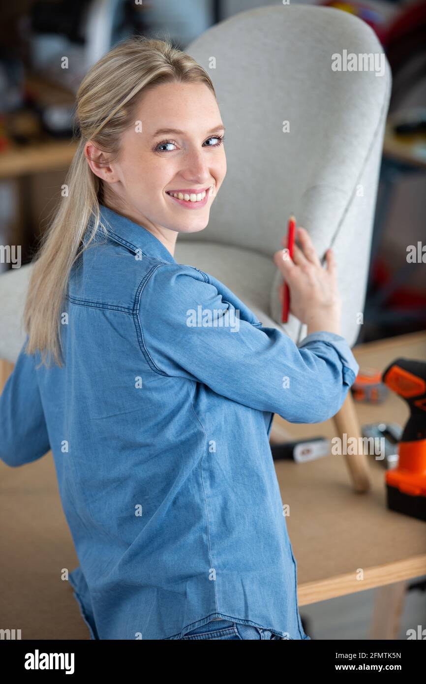 Junge professionelle Dekorateurin während der Polsterung des Sessels Stockfoto