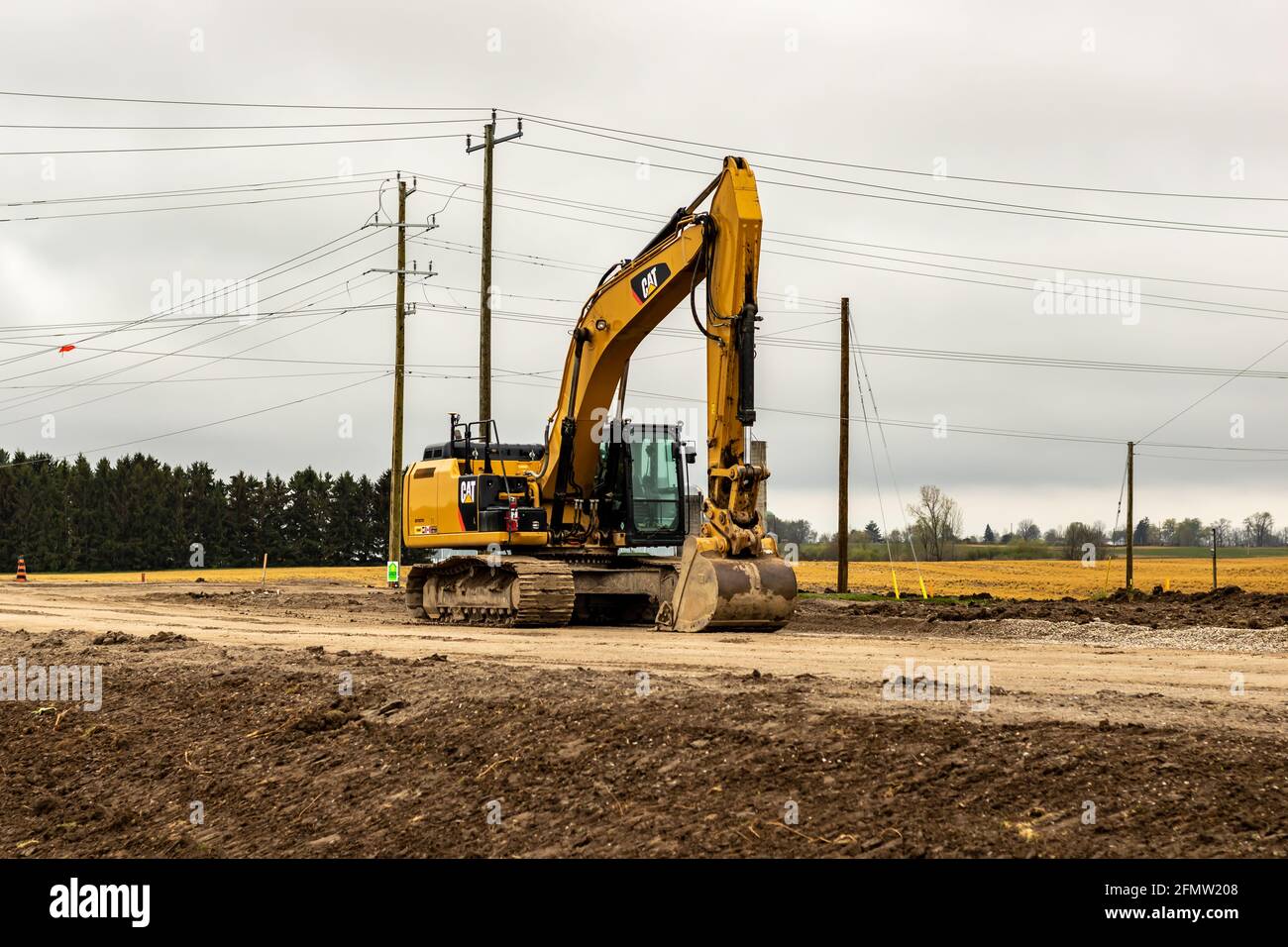 Der Bagger der Marke Caterpillar sitzt am Ende des Tages auf einer Straßenbaustelle auf dem Bill Martin Pkwy, St. Thomas, Ontario, Kanada, leer. Mai 4 2021. Stockfoto