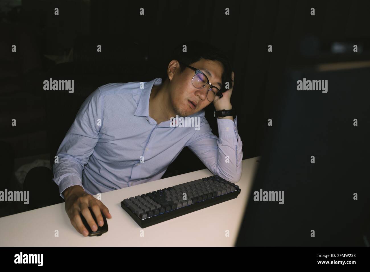 Junger asiatischer Geschäftsmann, der in einem Unternehmensbüro arbeitete, arbeitete überarbeitet. Männliche Büroangestellte während der Überstunden in der Nacht zu schlafen Stockfoto
