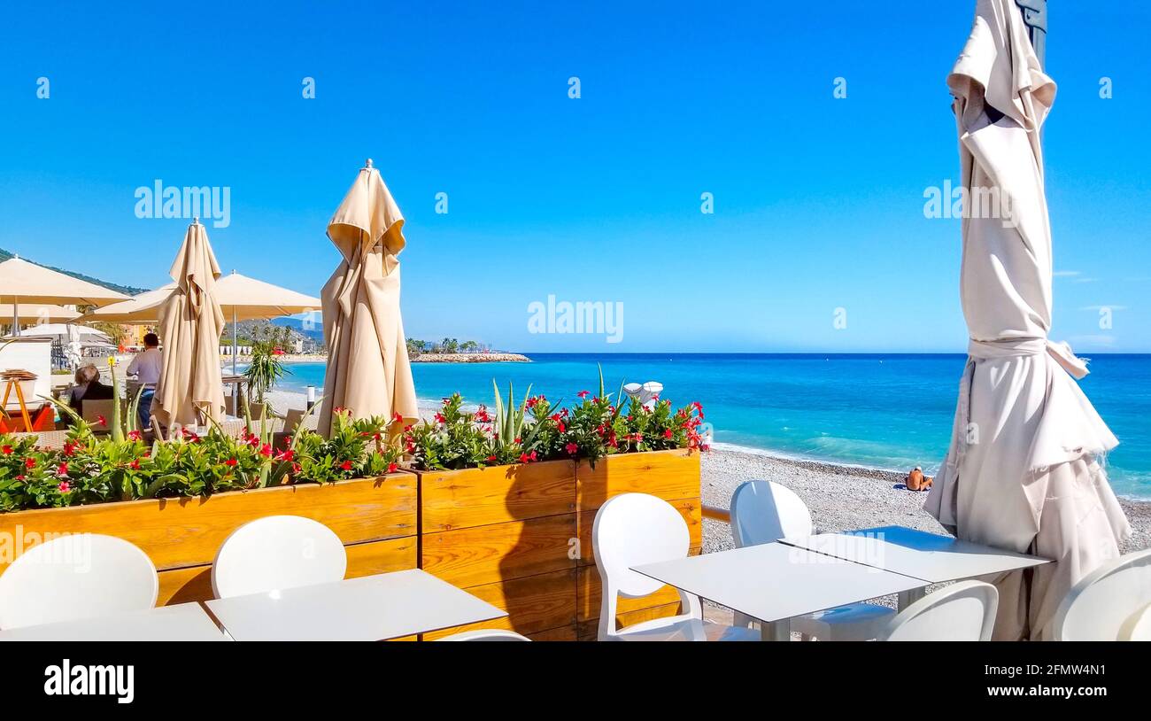 Ein Strandcafe mit Außenterrasse am Casino Beach oder Plage du Casino an der französischen Riviera in der Stadt Menton, Frankreich, im Sommer. Stockfoto