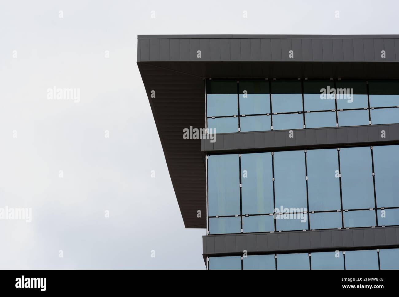 Bauplatzierung von Glasfensterwänden in einem neuen generischen Büro Gebäude gegen bewölkten weißen Himmel Stockfoto