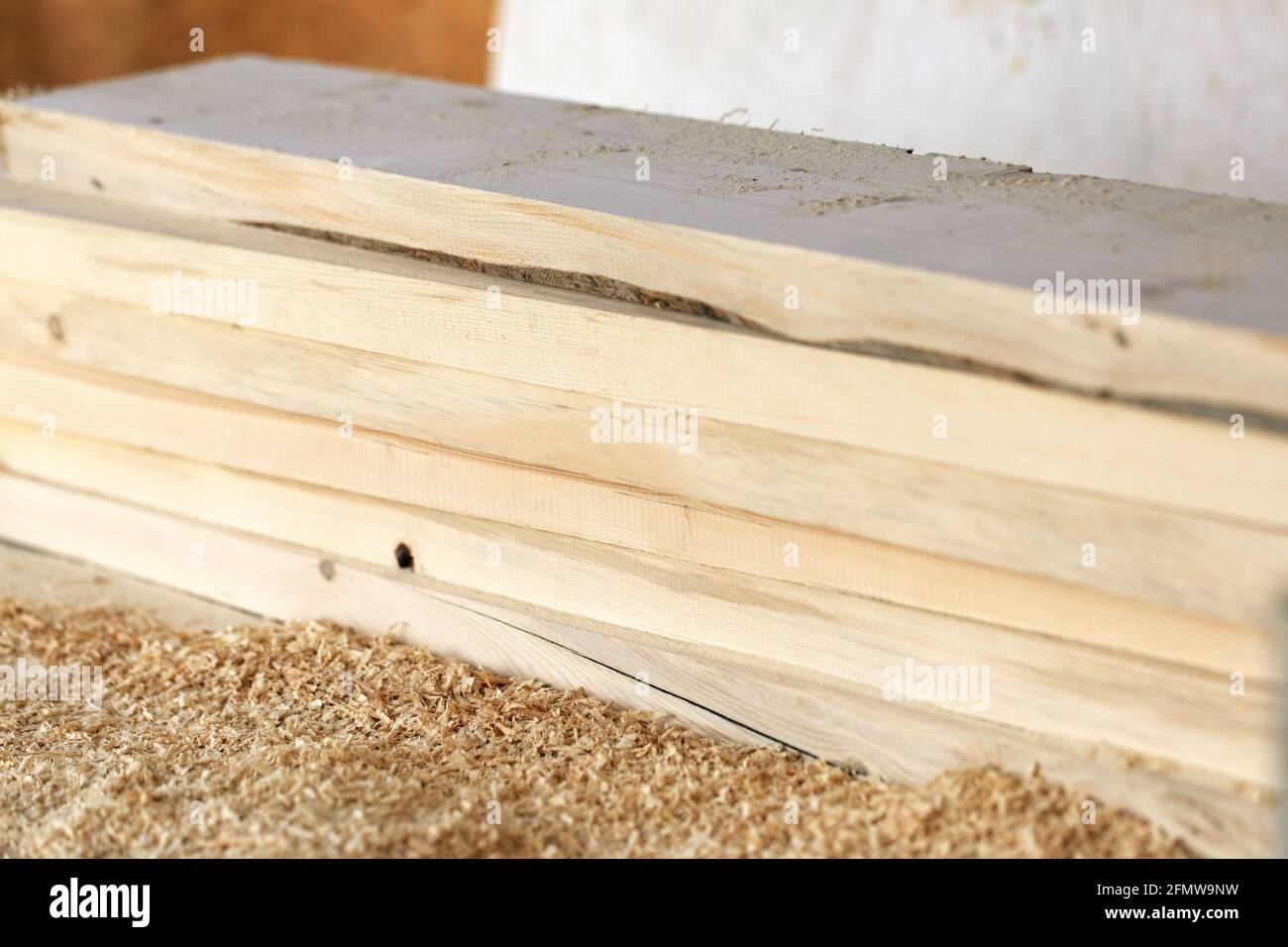 Selektive Fokussierung des Stapels von bearbeiteten Holzplanken mit Span auf verschwommenem Wandhintergrund. Reparatur Bau von Haus oder Schuppen. Holzwerkstatt Stockfoto