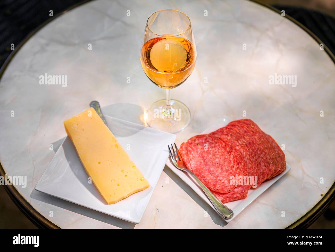 Ein Glas Sekt auf einem Tisch im Freien mit Käse und Salami auf einem Teller auf einem Weingut im Frühjahr in Napa Valley, Kalifornien, USA Stockfoto