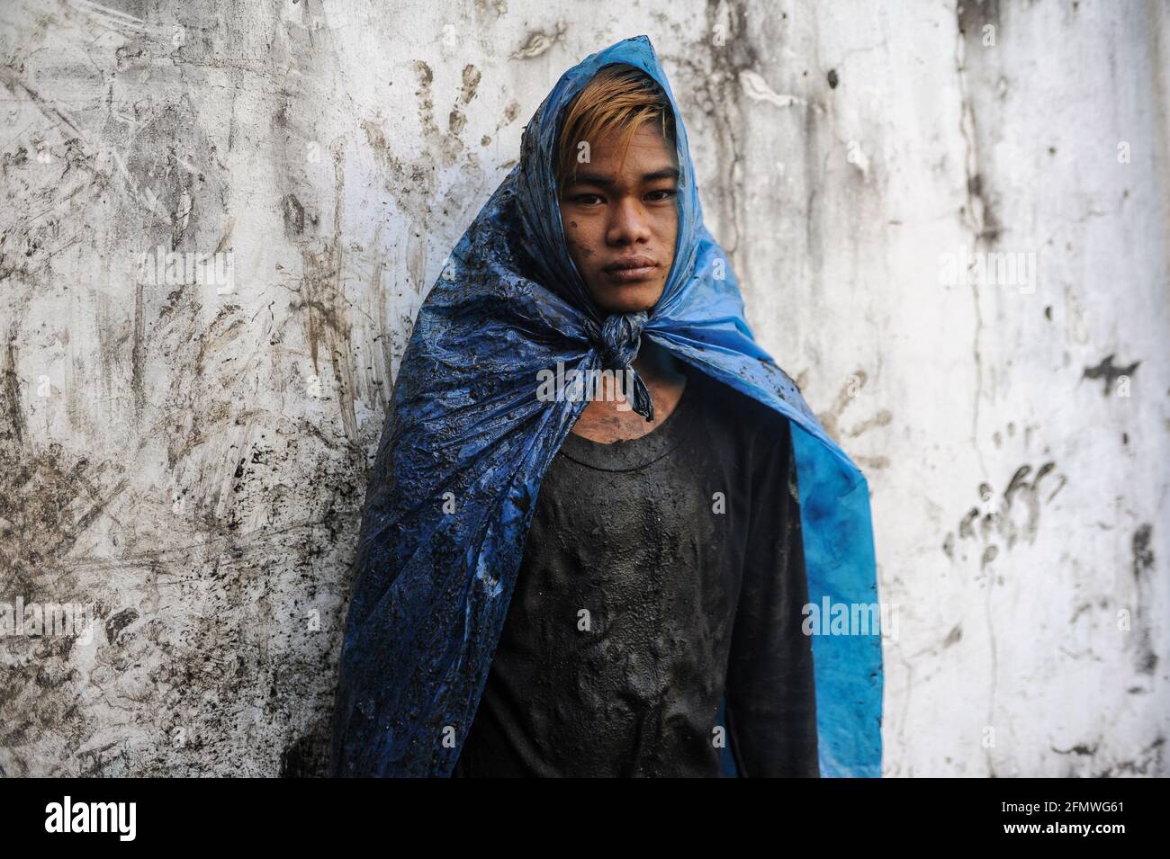 19.02.2014, Yangon, Myanmar, Asien - Porträt eines jungen Abwasserreinigers, der einfache Schutzkleidung aus zerrissenen Plastiktüten trägt, die Abflüsse reinigt. Stockfoto