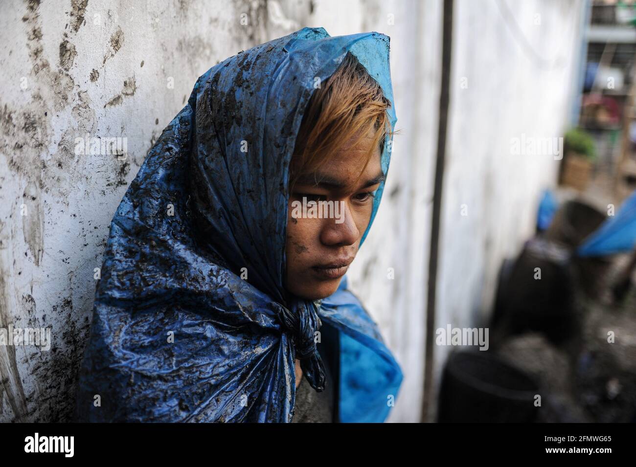 19.02.2014, Yangon, Myanmar, Asien - Porträt eines jungen Abwasserreinigers, der einfache Schutzkleidung aus zerrissenen Plastiktüten trägt, die Abflüsse reinigt. Stockfoto