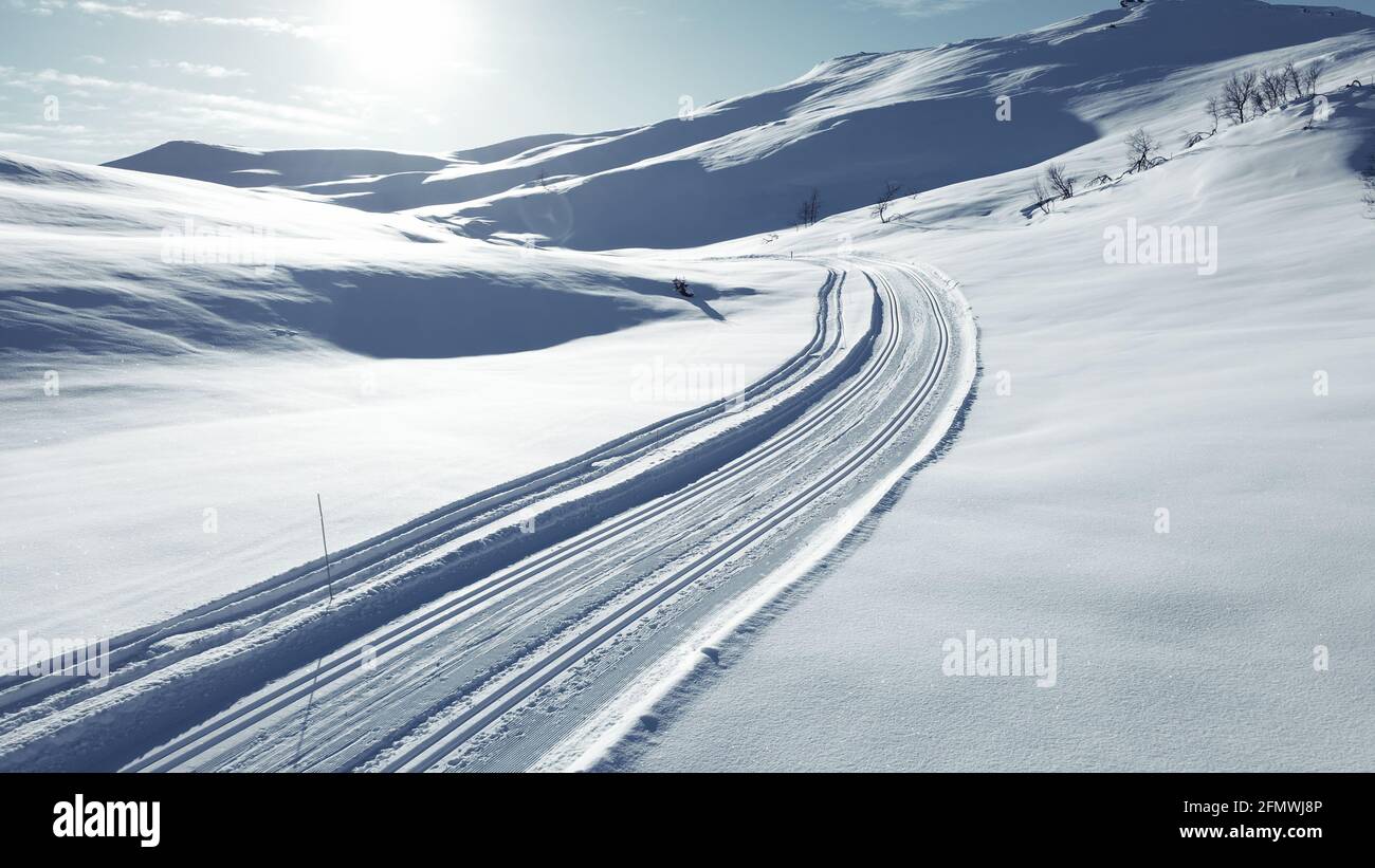 Langlaufloipe, die durch einen atemberaubenden schneebedeckten Berg führt. Stockfoto
