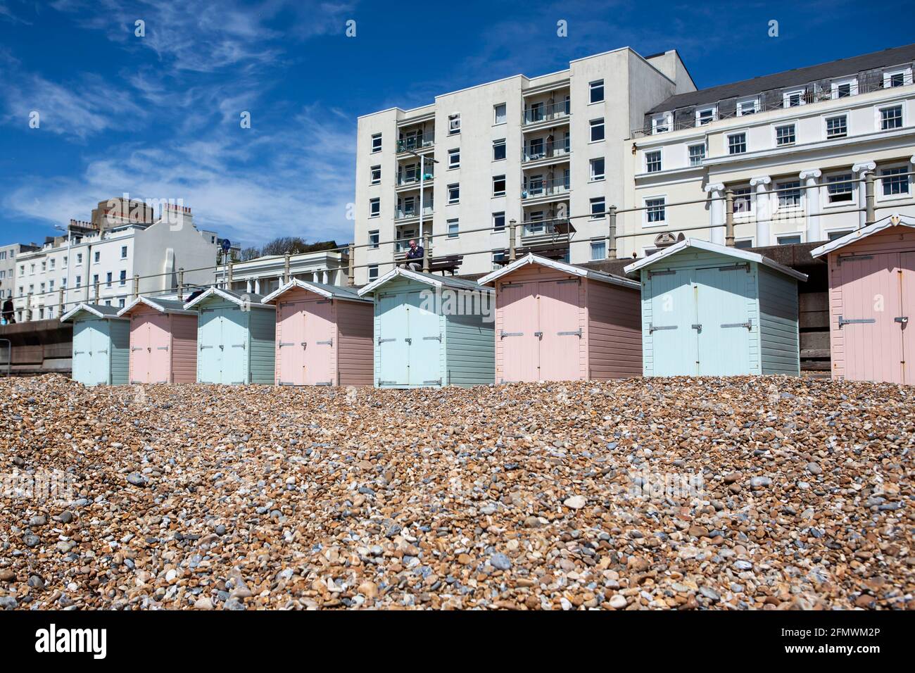 Strandhütten in Pastellfarben mit weißem Hotel in St. Leonards East Sussex Stockfoto