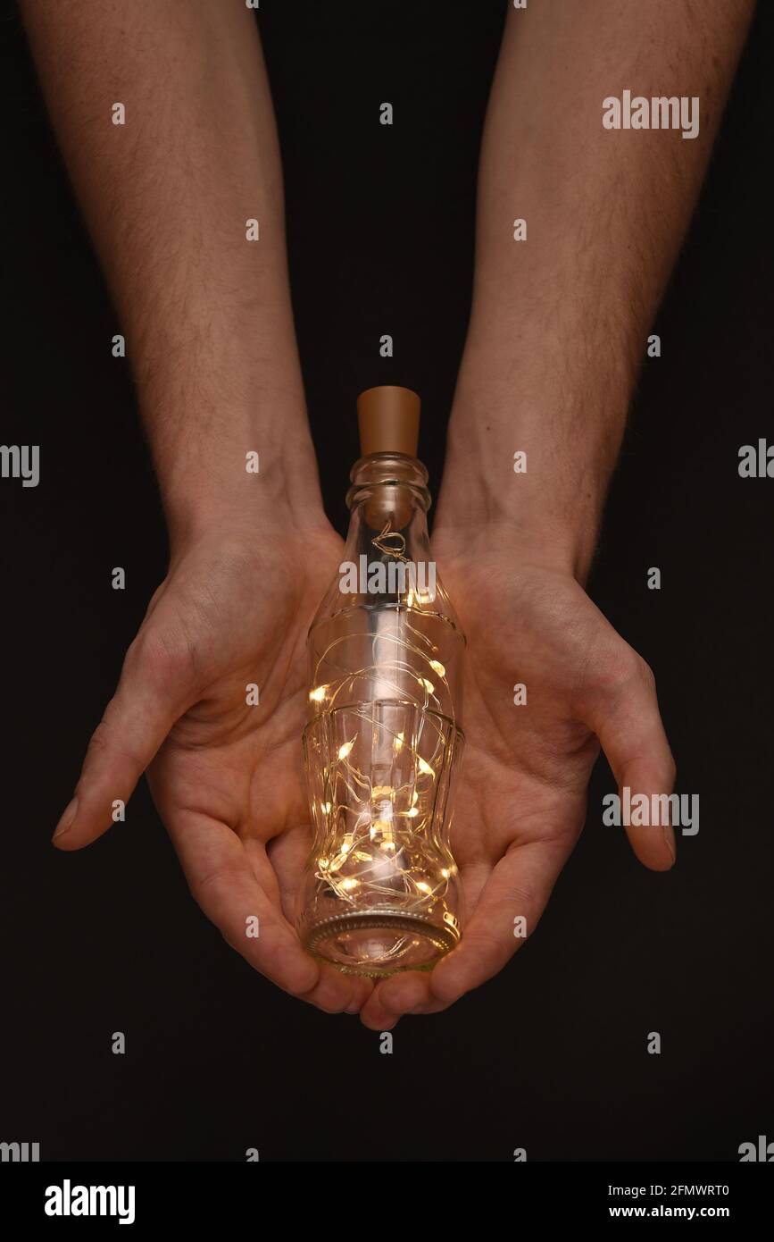 Hand hält Feenlichter in einer Flasche, Stockfoto