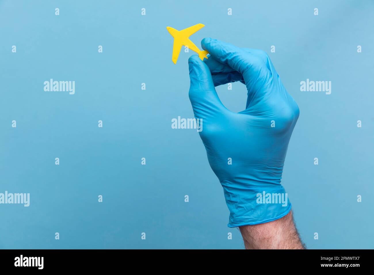 Eine Person, die einen medizinischen OP-Handschuh mit einem gelben Handschuh trägt Reisen Sie mit dem Flugzeug Stockfoto