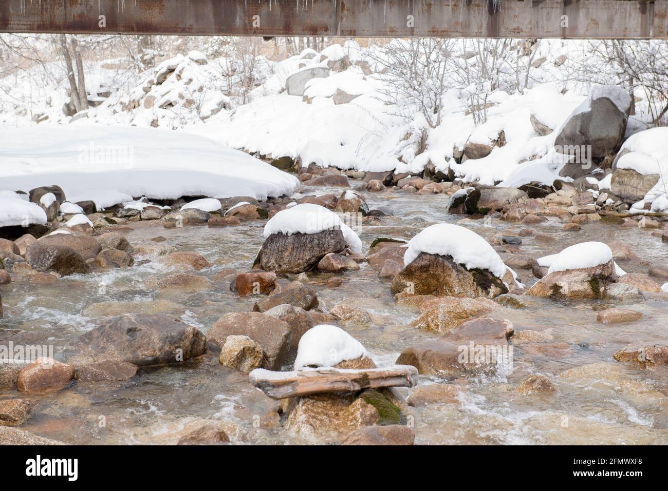 Bergfluss mit Steinen im Schnee Stockfoto