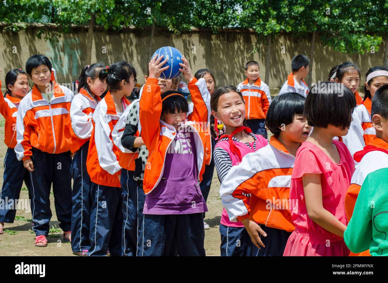 Schüler einer ländlichen Schule in Qufu, Shandong, China, haben einen freundschaftlichen Wettbewerb mit über und unter Spiel. Stockfoto