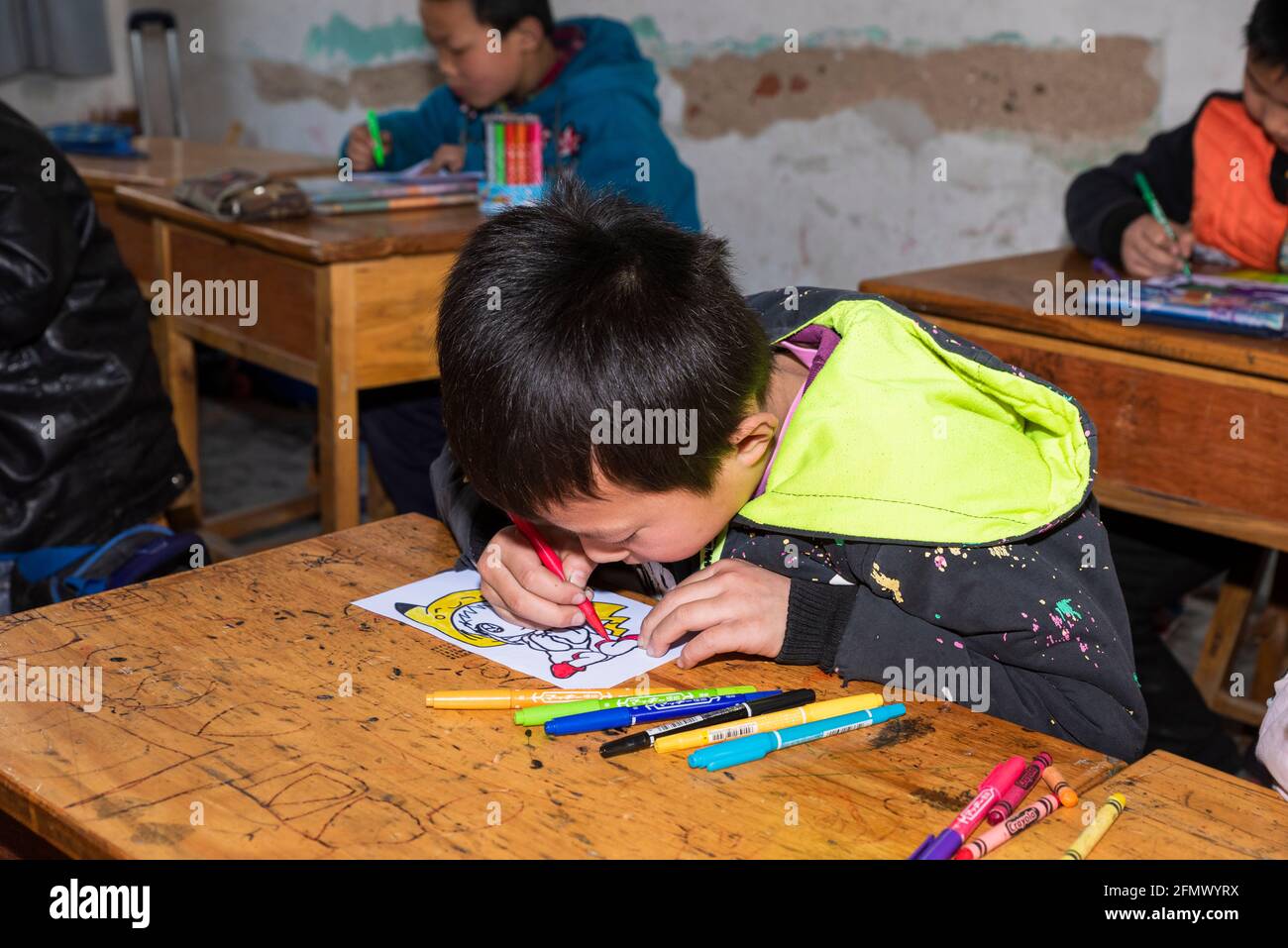 Schüler einer Grundschule im ländlichen China arbeiten an einem Kunst- und Handwerksprojekt. Stockfoto