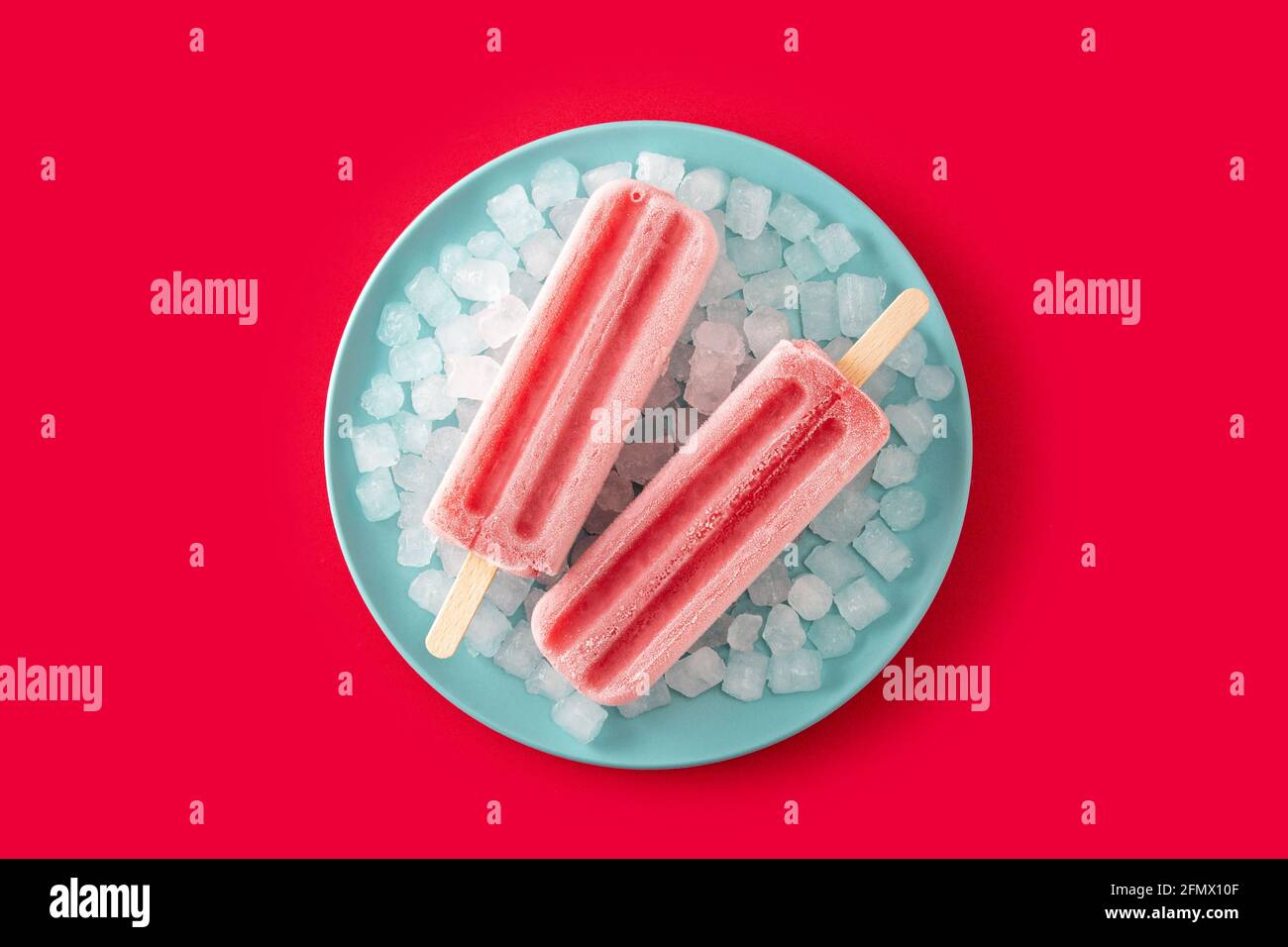 Erdbeerpopsicles mit Eis auf rotem Hintergrund Stockfoto