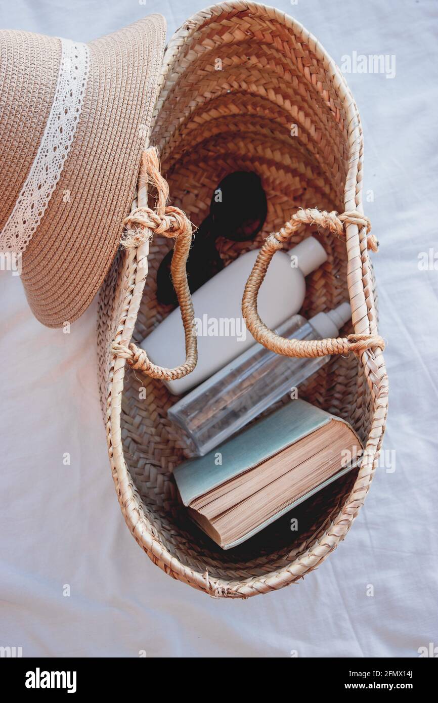 Vertikales Bild einer Sommertasche mit Sonnencreme, einem Buch und einer Sonnenbrille darauf. Der perfekte Ort, um einen sonnigen Tag am Strand zu genießen. Sommerkonzept 2021. Stockfoto