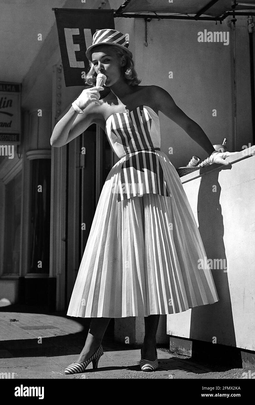 Mode, 50er Jahre, Damenmode, Frau mit Hut und ähnlichem Sommerkleid, Eis essen, ZUSÄTZLICHE-RIGHTS-CLEARANCE-INFO-NOT-AVAILABLE Stockfoto