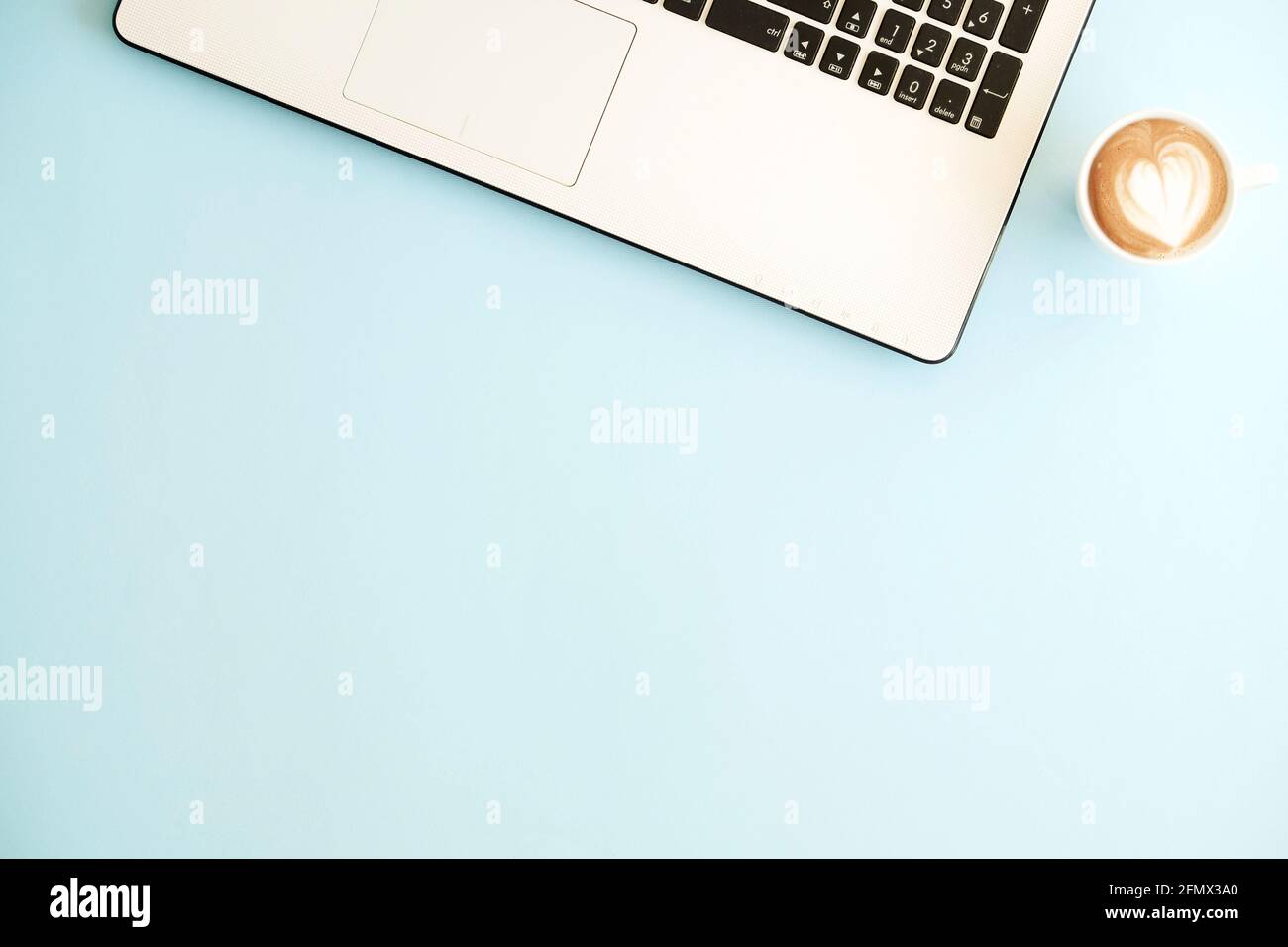 Minimalistisches, flaches Design aus schwarzem und weißem Laptop-Computer Tastatur und Tasse Cappuccino auf babyblauer Oberfläche Tischhintergrund in b Stockfoto