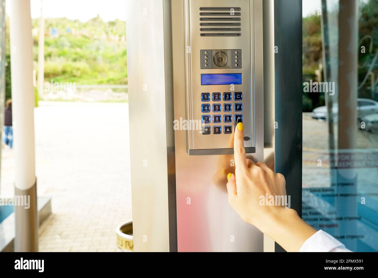 Nahaufnahme der Frau Hand Eingabe von Sicherheits-System-Code, Drücken der Taste mit Zeigefinger auf moderne Gegensprechanlage mit blauem lcd-Bildschirm in der Nähe Eingang d Stockfoto