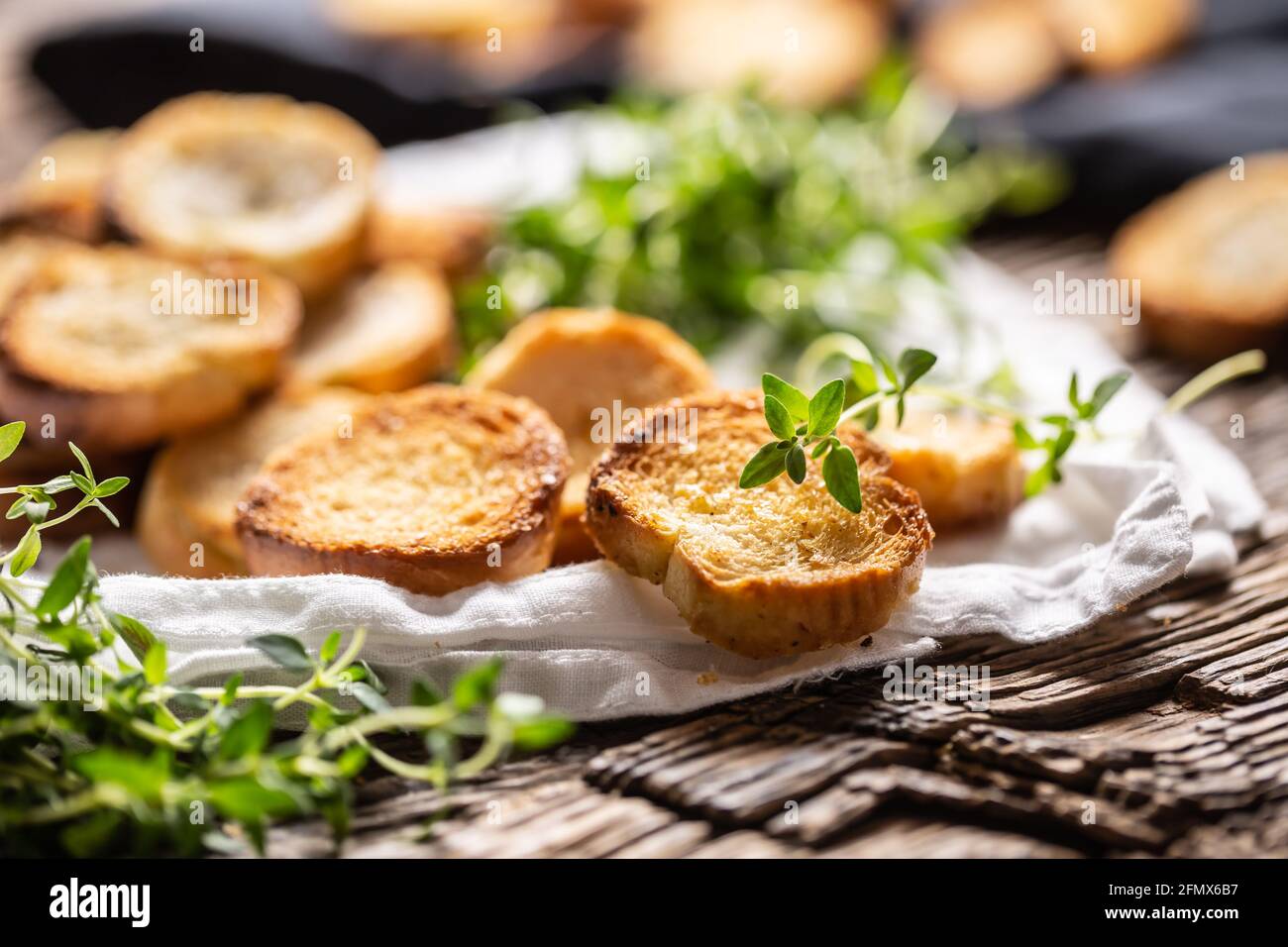 Kleine runde, salzige Mini-Backrollen mit herrlich knusprigem Geschmack und goldischer Farbe aus gebackenem Brot, die im Papier oder Geschirrtuch mit Thymian serviert werden. Stockfoto