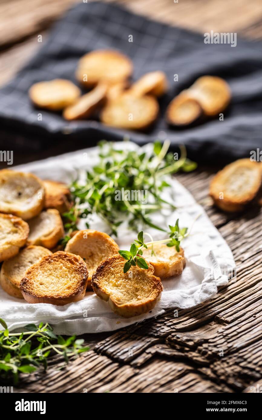 Kleine runde, salzige Mini-Backrollen mit herrlich knusprigem Geschmack und goldischer Farbe aus gebackenem Brot, die im Papier oder Geschirrtuch mit Thymian serviert werden. Stockfoto