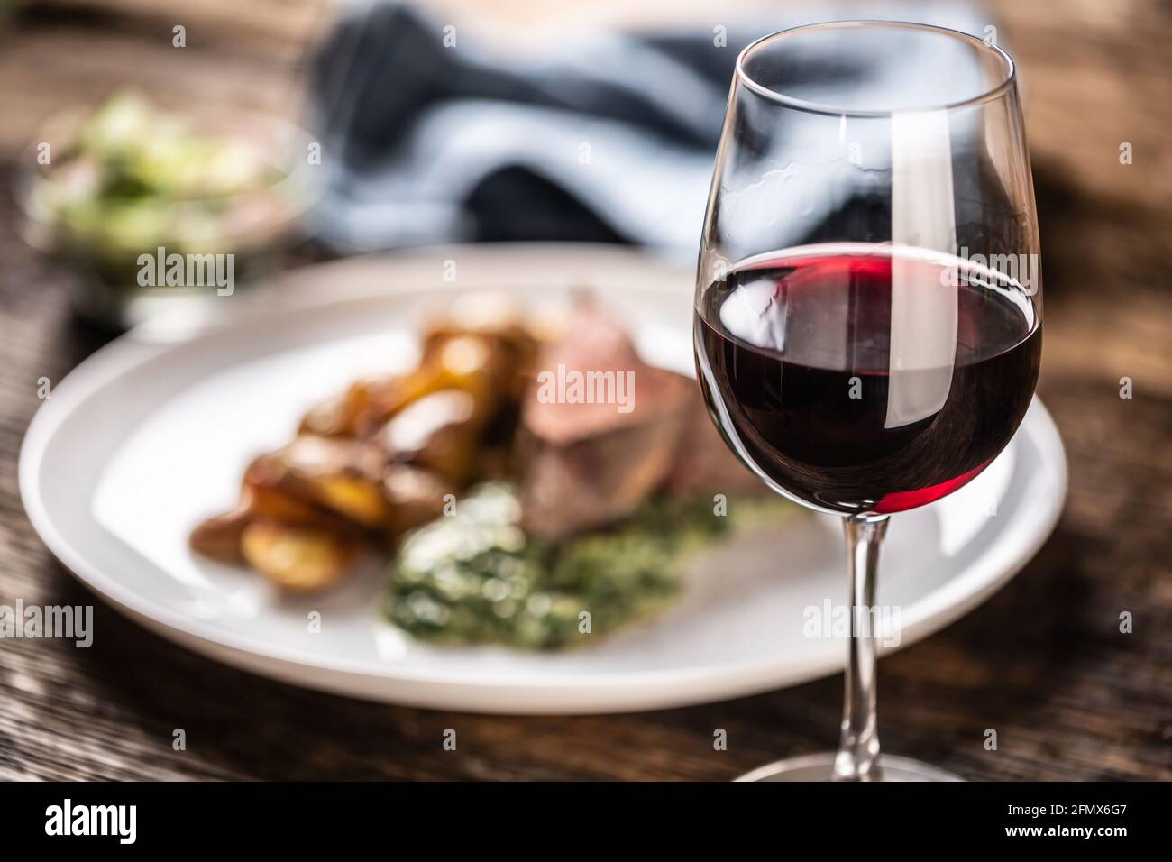 Rotwein als typischer durchschnitt zu einem roten Fleisch sous vide Steak mit gebratenen Kartoffeln, Spinat Dip und frischem Salat auf einem weißen Porzellanteller auf t serviert Stockfoto