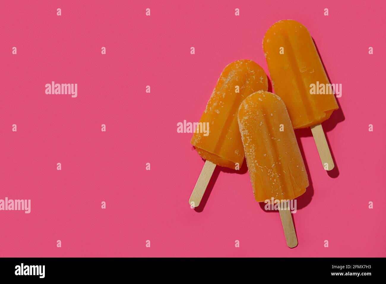 Mango- oder Karamell-Eis-Sticks auf rosa Hintergrund Stockfoto