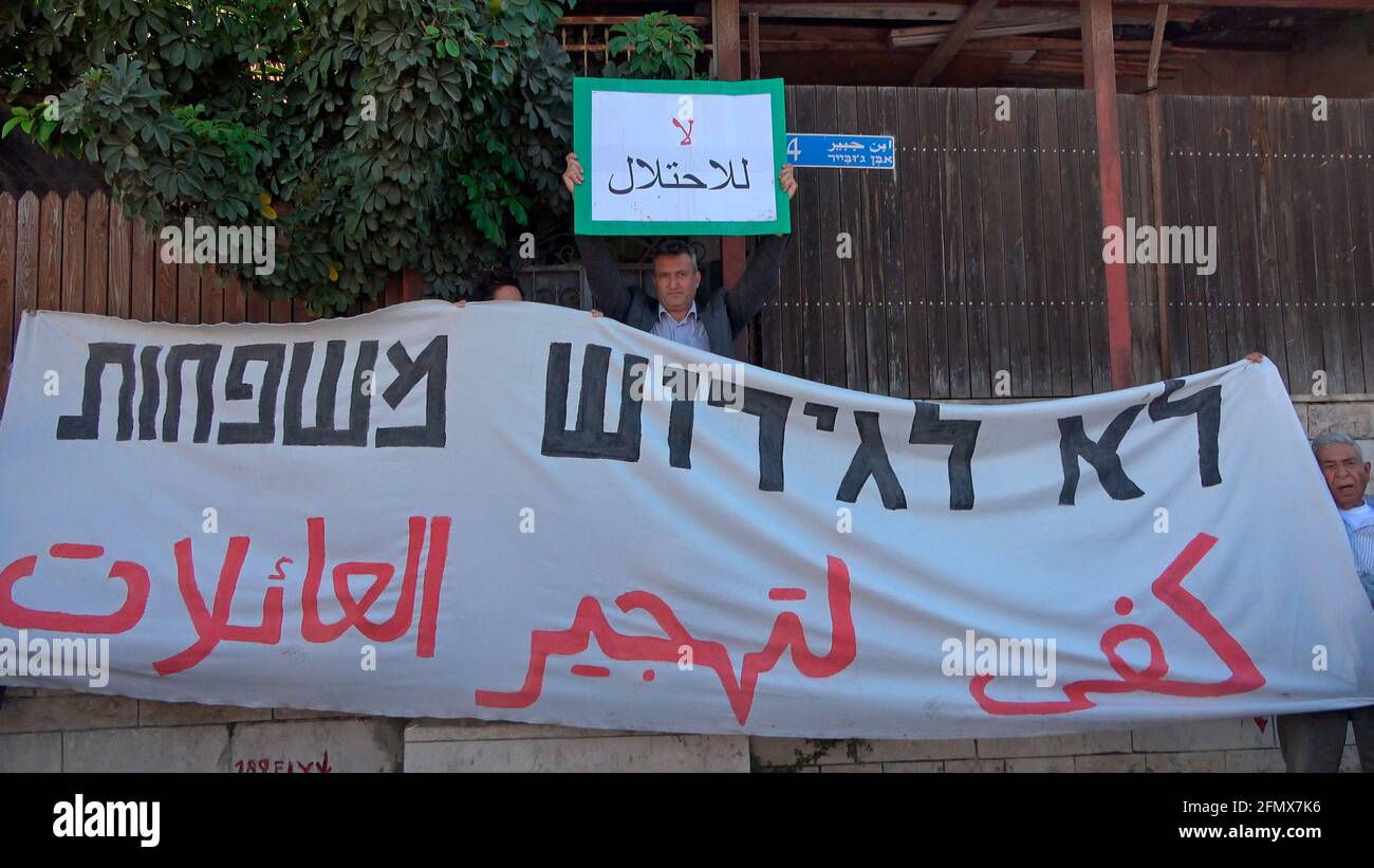 Ein linker israelischer Aktivist und ein palästinensischer Mann halten ein Banner vor einem Haus, das von jüdischen Siedlern besetzt wurde, während sie am Mai an einer Demonstration gegen die Vertreibung palästinensischer Familien aus ihren Häusern und Siedlungsaktivitäten in Scheich Jarrah, einem überwiegend palästinensischen Viertel, teilnehmen 07, 2021, in Ostjerusalem, Israel. Dutzende palästinensische Bewohner von Scheich Jarrah stehen seit Jahren vor einer möglichen Räumung, inmitten verstärkter Bemühungen von rechten Siedlergruppen, die behaupten, dass das Land vor der Gründung Israels im Besitz von Juden war, als 1948. Die Drohung der Räumung hat l Stockfoto
