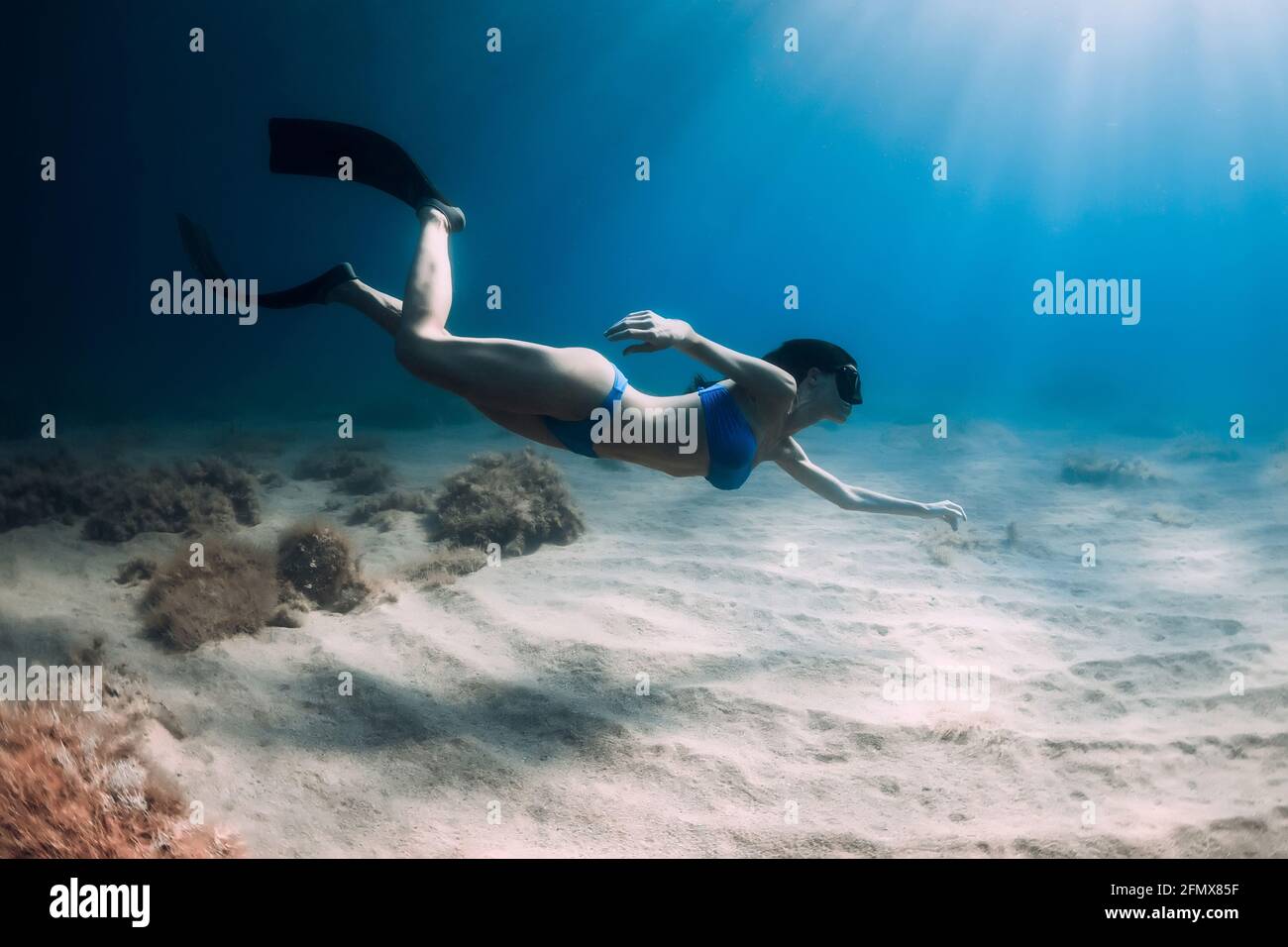 Attraktive Freitaucherin Frau mit Flossen tauchen tief unter Wasser im Meer. Stockfoto