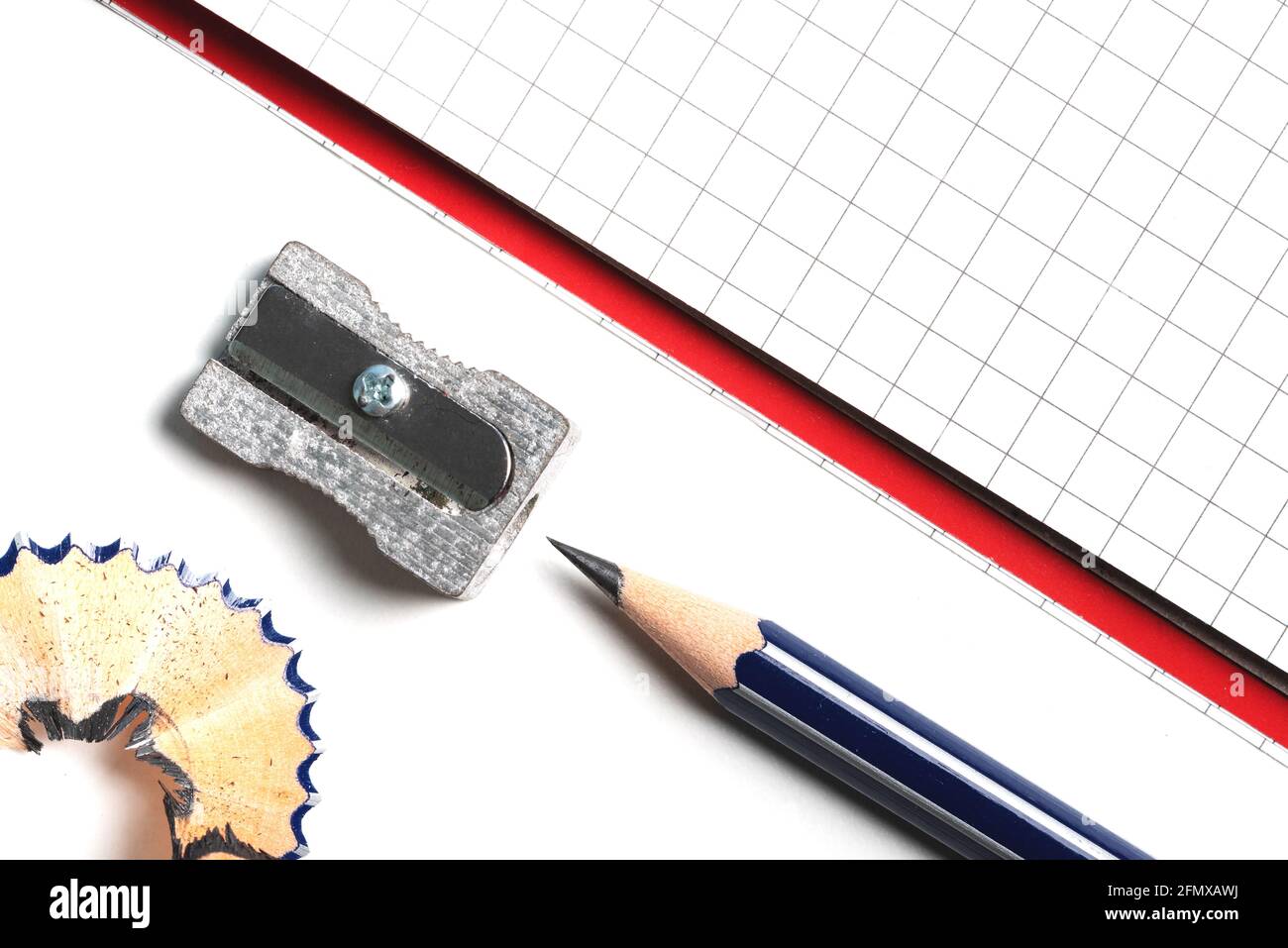 Direkt über Nahaufnahme von Bleistiftspitzer, Bleistift und Notizblock auf weißem Schreibtisch Stockfoto