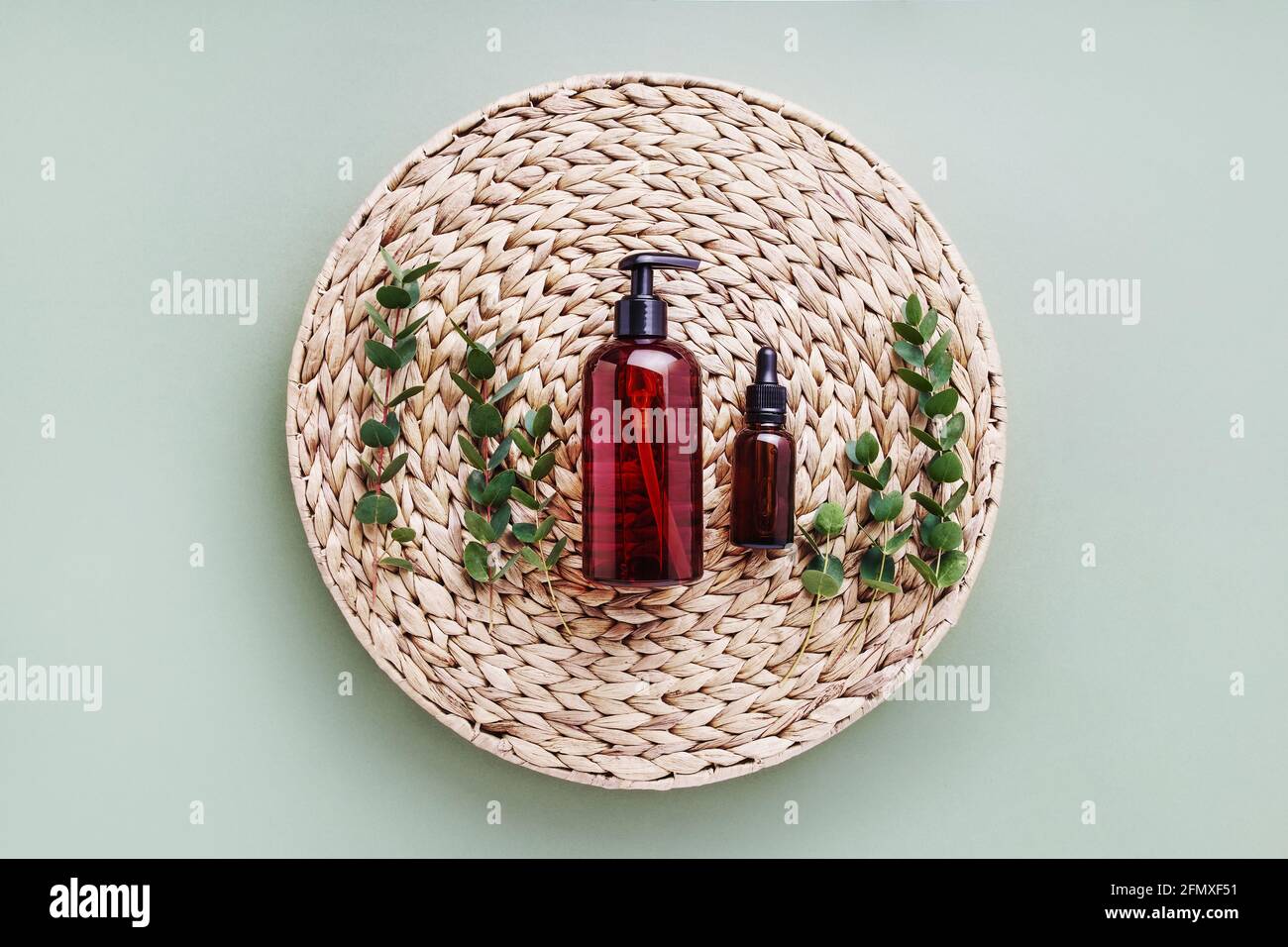 Tropferflasche mit ätherischem Öl oder Serum, Eukalyptus und dunkler Spender Flasche Duschgel auf Rattan-Hintergrund. Beauty- und SPA-Konzept. Flache Lay, Stockfoto