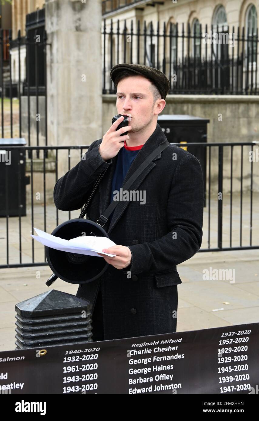 London, Großbritannien. Ein Demonstrator liest aus einer Liste von Opfern. Names Not Numbers, die Organisation, die sich an diejenigen erinnern und für diese werben will, die ihr Leben aufgrund von Regierungsnachlässigkeit und mangelndem Handeln während der COVID-19-Krise verloren haben. Gegenüber Downing Street, Westminster. Stockfoto