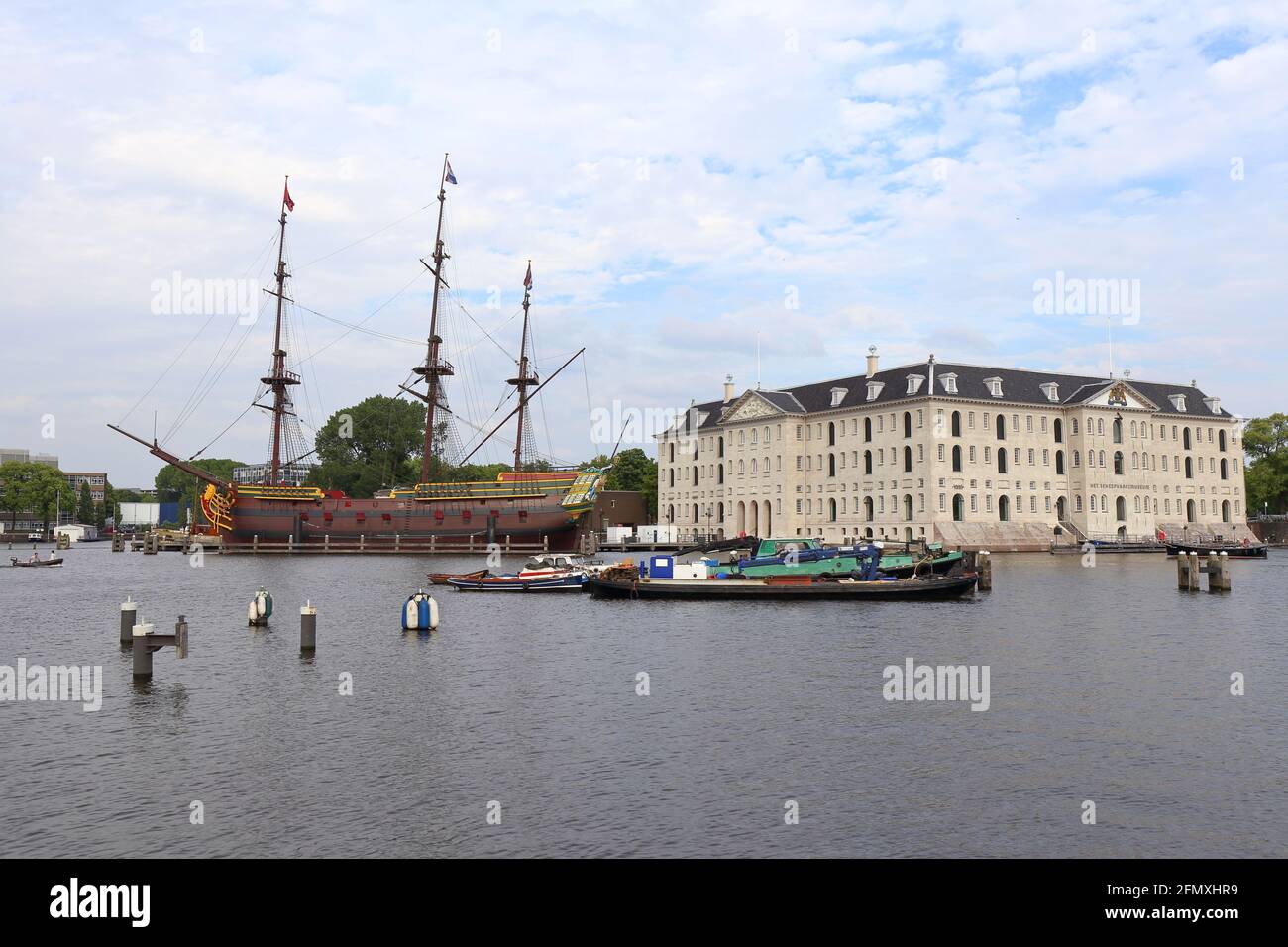 Segelboote mit Liegeplätzen und nationales Schifffahrtsmuseum und Nachbildung des Schiffs Amdterdam im Hintergrund in Amsterdam Stockfoto