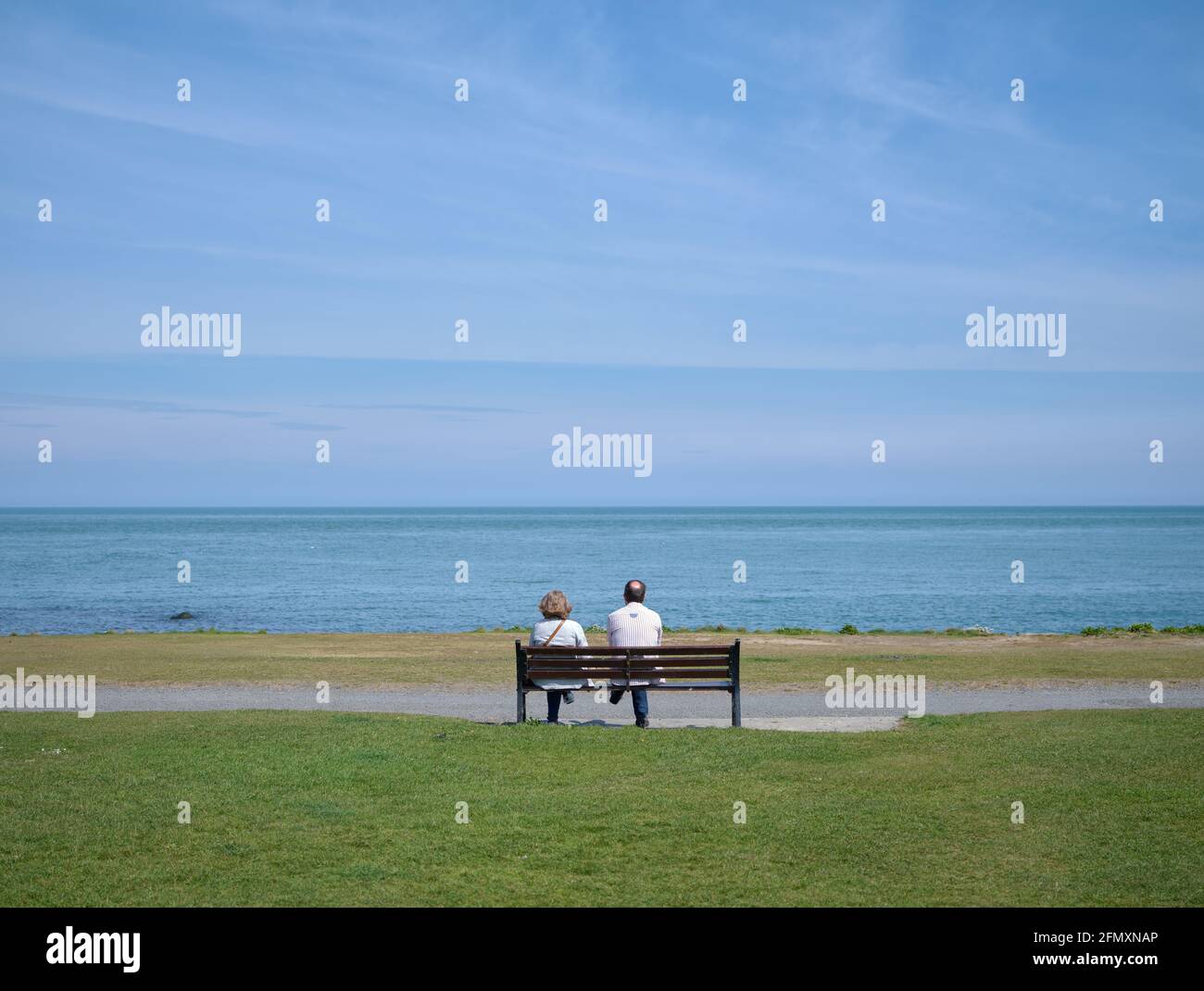 Ein Paar sitzt auf einer Bank mit Blick auf das Meer bei Skerries im Norden der Grafschaft Dublin, Irland. Stockfoto