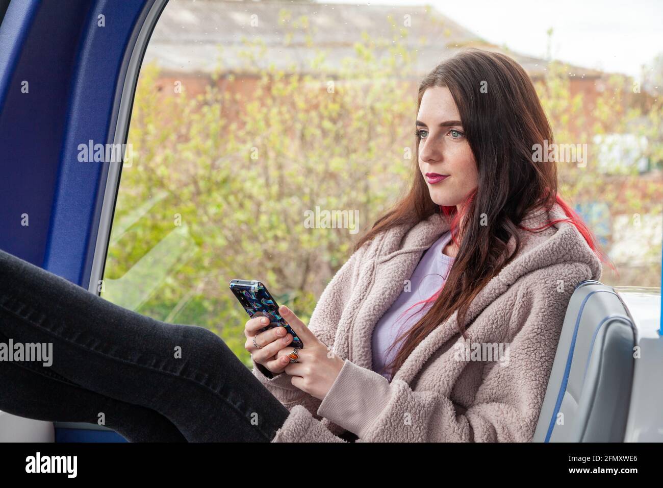 Eine junge Frau fährt mit dem Bus und starrt ruhig aus Das Fenster Stockfoto