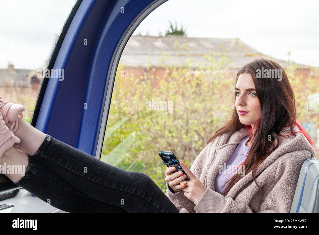Eine junge Frau fährt mit dem Bus und starrt ruhig aus Das Fenster Stockfoto