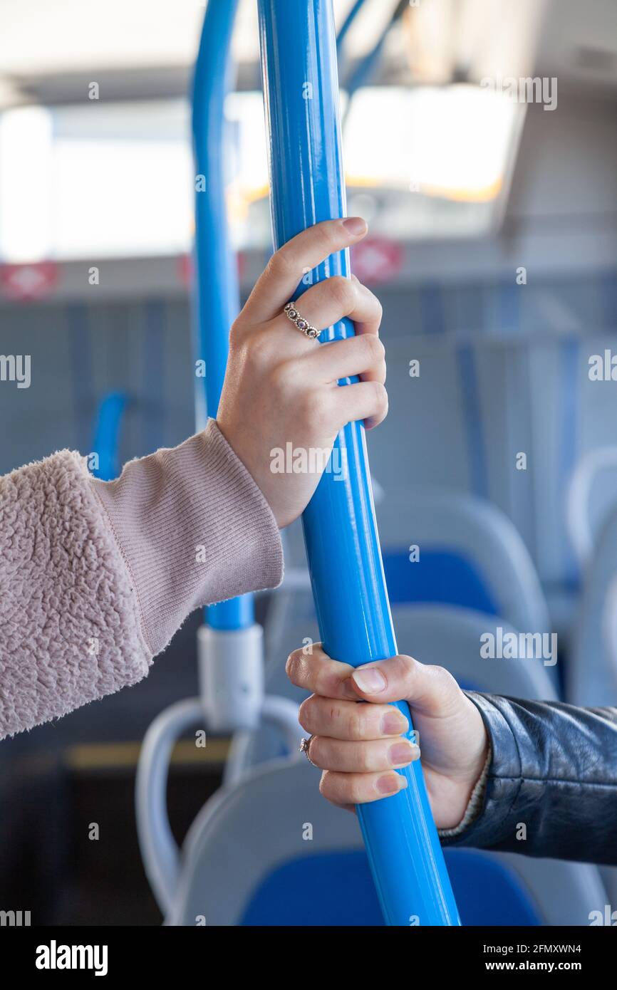 Zwei weibliche Hände, die eine Busschiene halten Stockfoto