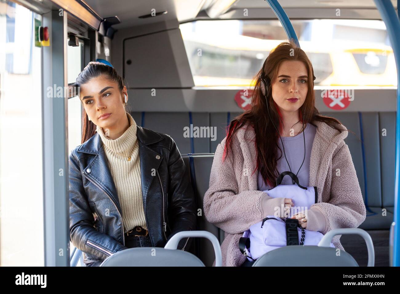 Zwei Frauen, die in einem Bus zusammen sitzen, sitzen nebeneinander und reden nicht. Stockfoto