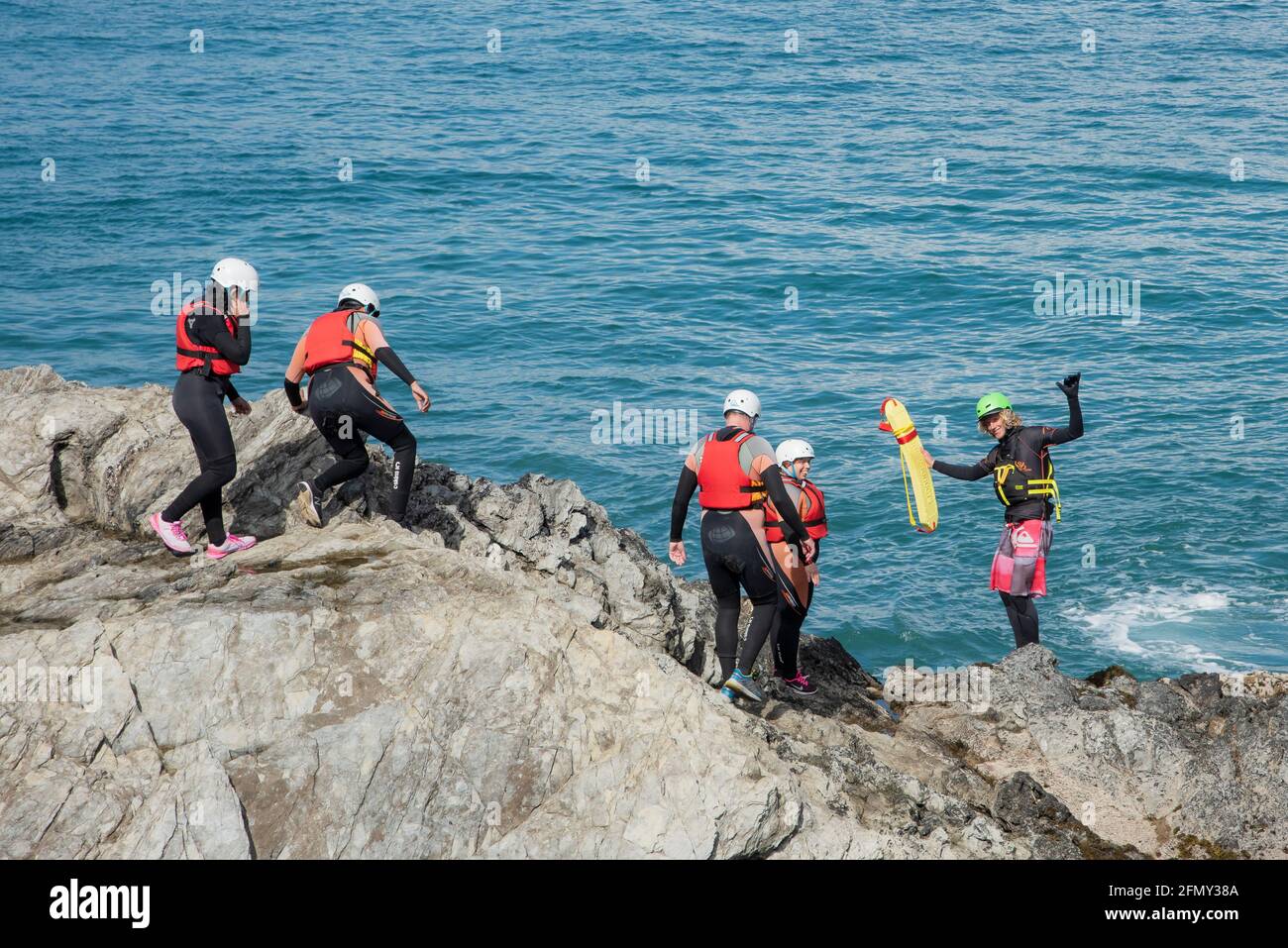 Urlauber, die sich mit ihrem kolenkenden Fremdenführer an der Küste von Towan Head in Newquay in Cornwall auf den Einstieg ins Meer vorbereiten. Stockfoto
