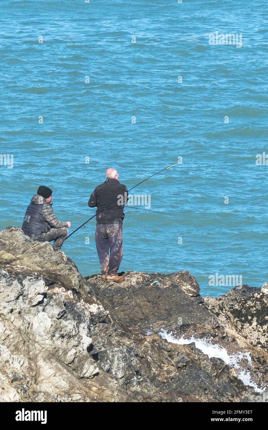 Reife Männer fischen von Felsen in Towan Head in Newquay in Cornwall. Stockfoto
