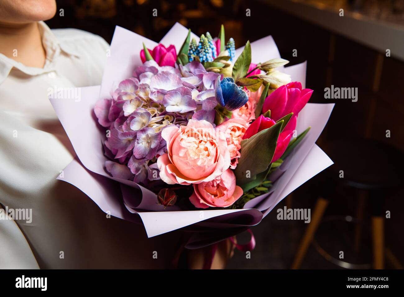 Das Mädchen hält in ihrer Hand einen herrlichen Strauß mit bunten frischen Blumen, EIN tolles Geschenk für jeden Anlass. Stockfoto