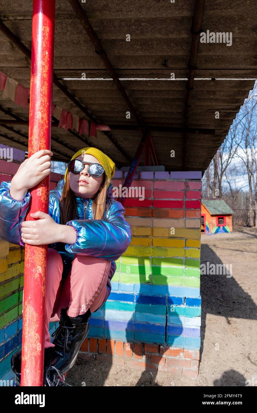 Das Teenager-Mädchen steht draußen in der Nähe einer regenbogenfarbenen Wand. Selbstliebe-Konzept. Lebensstil des Kindes. Stockfoto