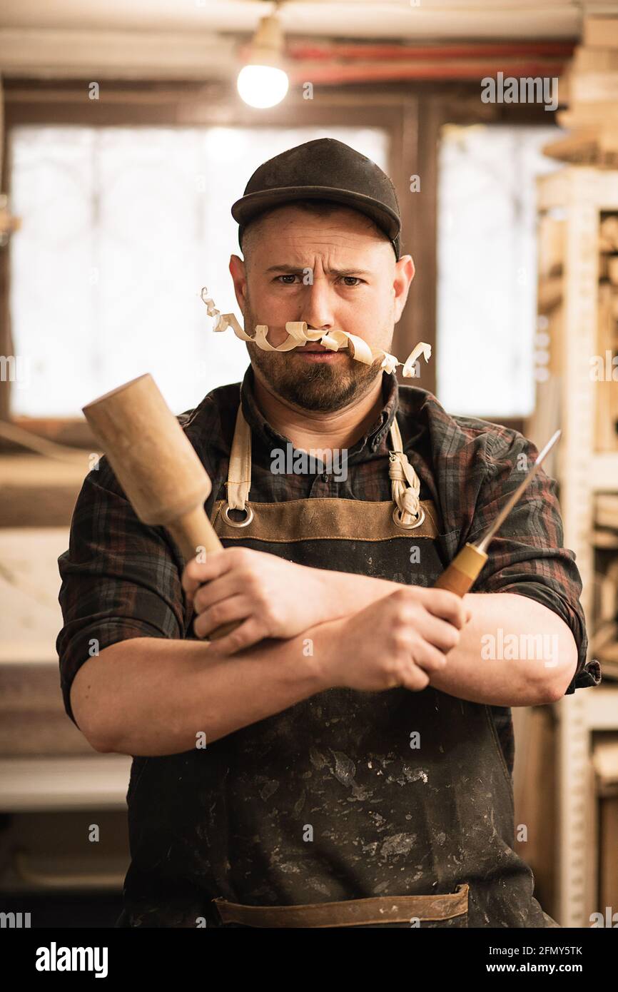 Lustiges Nahaufnahme-Porträt des Zimmermanns mit Späneschnurrbart und Werkzeugen Stockfoto