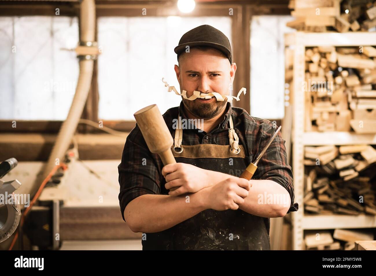 Humor lustiges Porträt des Zimmermanns mit Späneschnurrbart und Werkzeugen Stockfoto